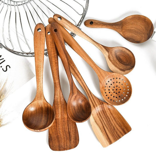 Six teak wood kitchen utensils on rustic cutting board